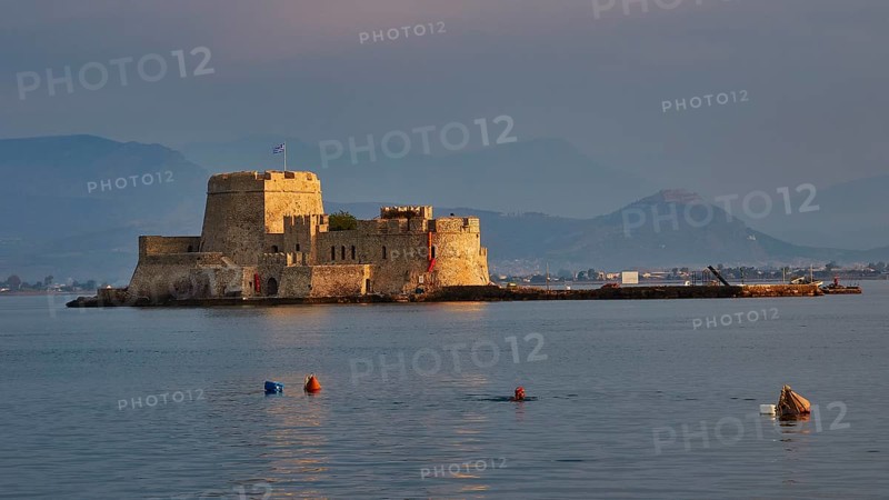 Bourtzi island fortress, old fortress on an island in the calm sea, surrounded by buoys and mountains in the evening light, Nauplion, Nafplion, Peloponnese, Greece