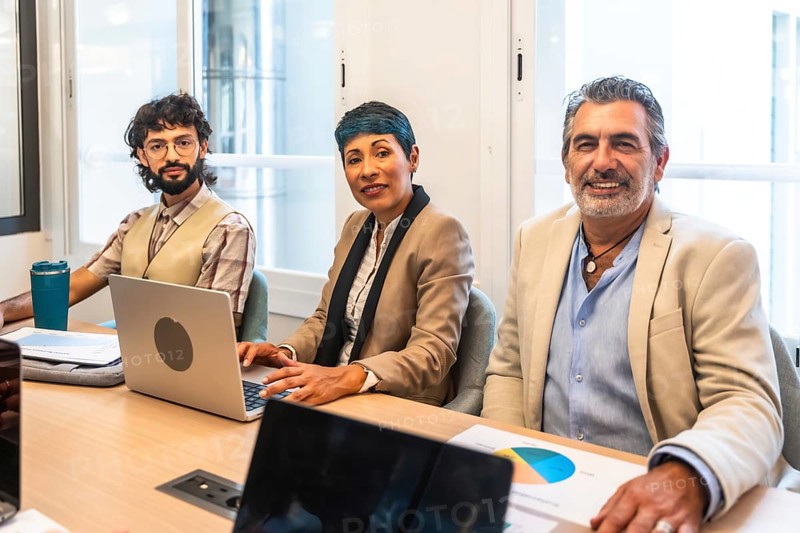 Diverse business colleagues working together around a table in a bright coworking office, smiling while planning a new business strategy and sharing ideas