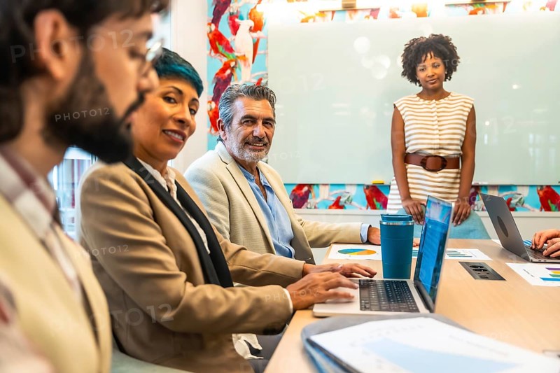 Diverse business colleagues holding a meeting or presentation, working and smiling in a colorful modern office space, discussing ideas and planning work