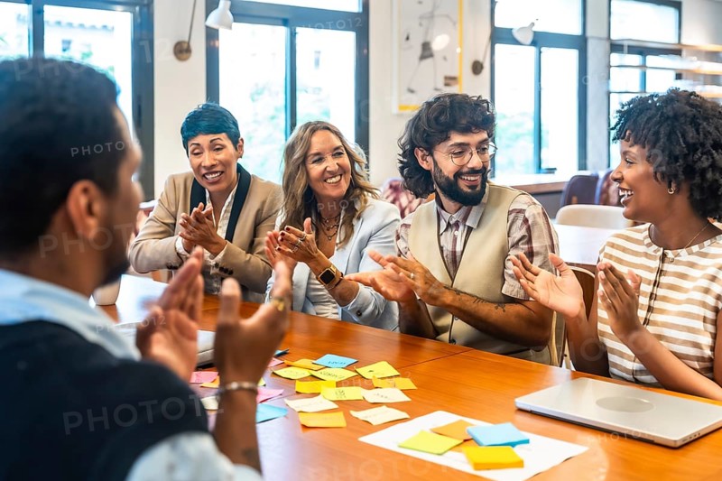 Coworkers clapping and smiling during a collaborative office meeting, showcasing teamwork, appreciation, and positive engagement in a modern coworking space