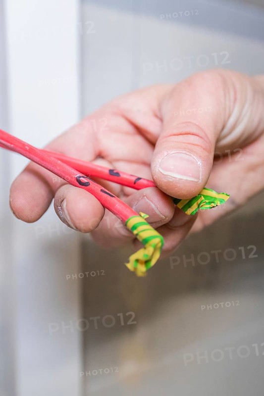 Hand holds red and green marked cable ends close to the camera