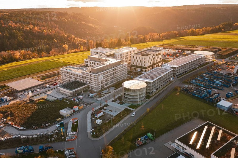 Modern buildings surrounded by fields and hills at sunset, aerial view, new hospital, Calw health campus, Black Forest, Germany