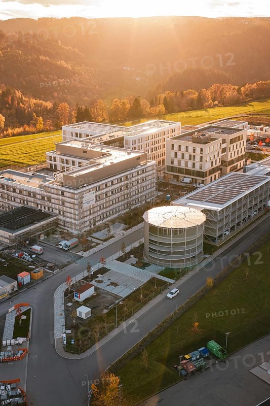 Modern buildings in rural landscape with forests and fields at sunset, aerial view, new hospital, Calw health campus, Black Forest, Germany