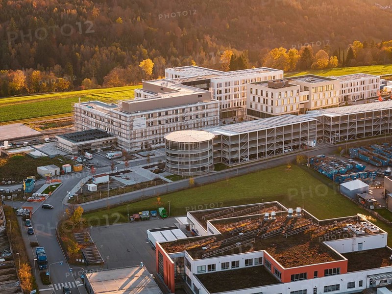 Building complex surrounded by autumn landscape and industrial area, aerial view at sunset, new hospital, Calw health campus, Black Forest, Germany