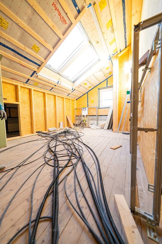 Conversion in an attic with visible wiring and incoming daylight through skylights