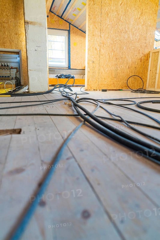 Construction site situation with scattered cables on a wooden floor. An incoming light source illuminates the room