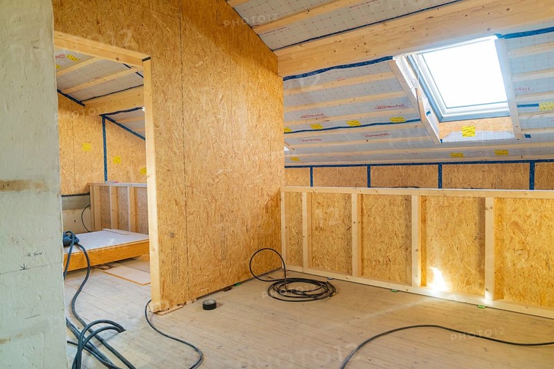 A bright attic room under construction with wooden lining