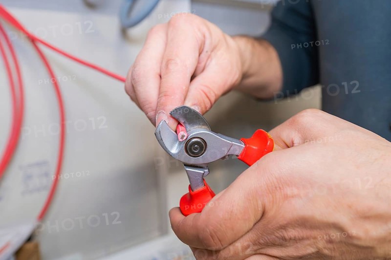Close-up of a hand cutting a cable with pliers