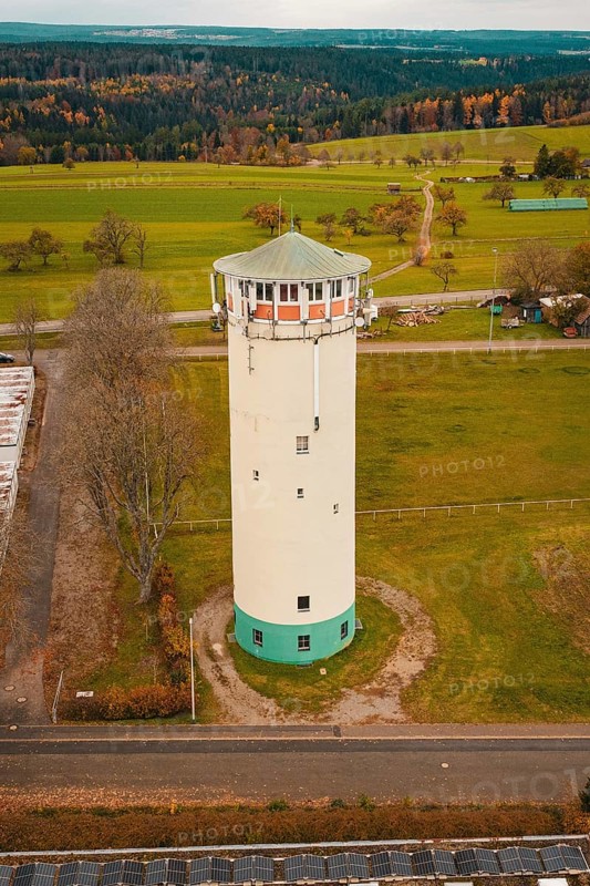 White water tower in rural autumn landscape with green fields and autumnal trees, water tower, Pfalzgrafenweiler, Freudenstadt district, Germany