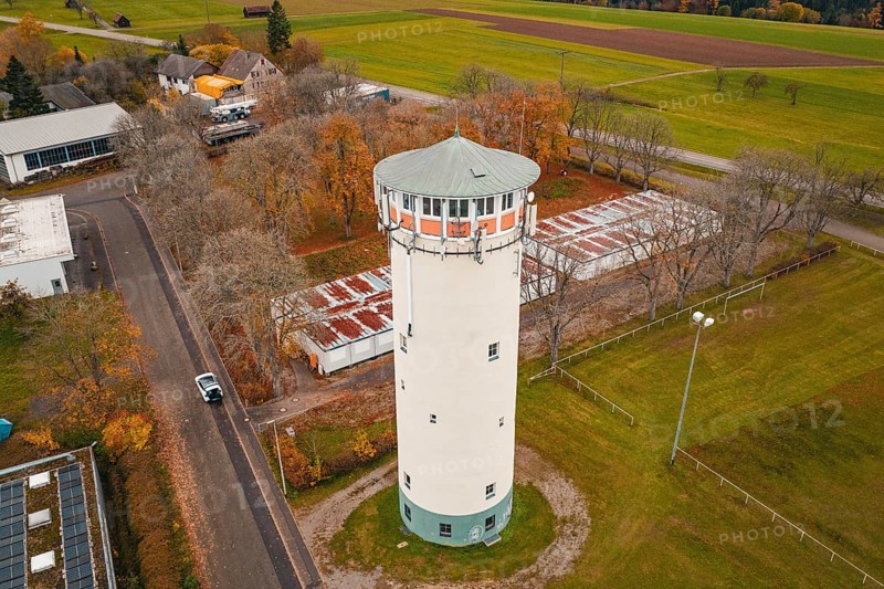 Water tower on a road with autumn trees in rural area, surrounded by small buildings, water tower, Pfalzgrafenweiler, Freudenstadt district, Germany