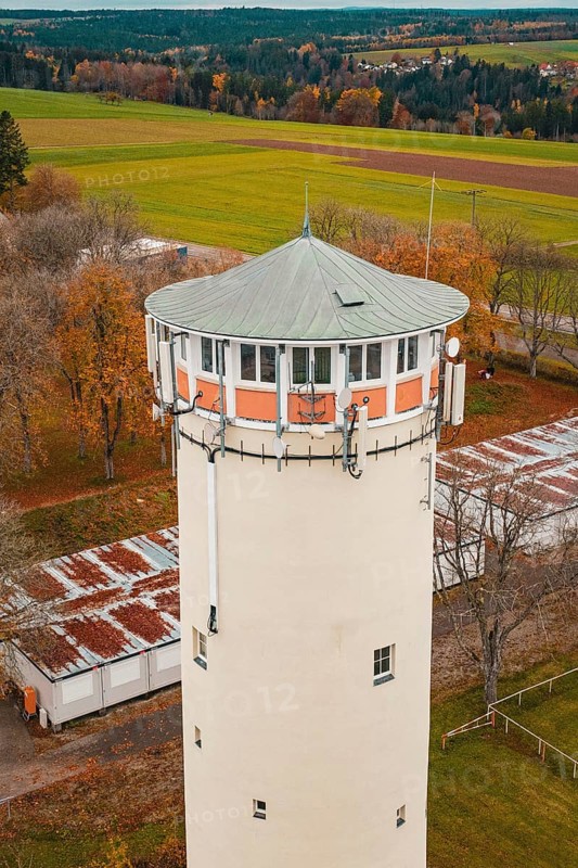 Close-up of the upper part of a water tower with green roof surrounded by autumn trees, Wasserturm, Pfalzgrafenweiler, Freudenstadt district, Germany