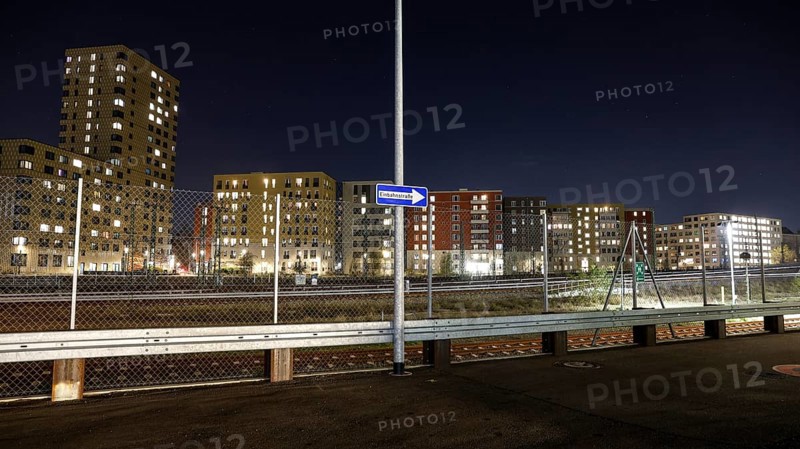 One way street on the fence, behind it a passing ICE train, illuminated apartments in a new housing development, Berlin, 23.11.2025, Berlin, Berlin, Germany