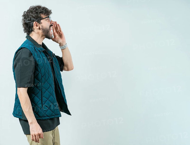 Casual young man in glasses shouting a promotion. Male person shouting an announcement isolated