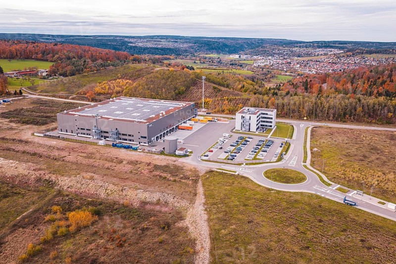 Large warehouse surrounded by hills and autumn trees, modern architecture, new Lindenrain industrial park, Calw, Black Forest, Germany