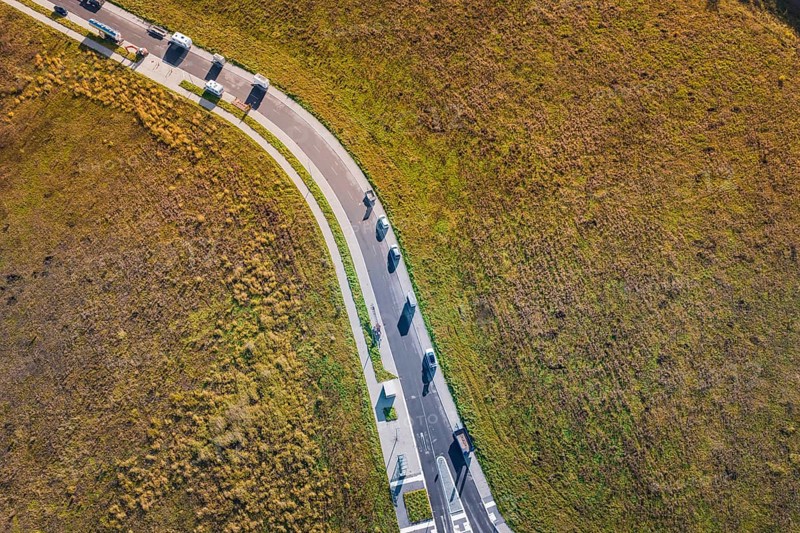 Curved road with cars through autumnal meadow landscape, new Lindenrain industrial park, Calw, Black Forest, Germany