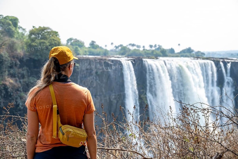 Tourist looking at waterfalls, water plunging into the depths, Victoria Falls, Zimbabwe
