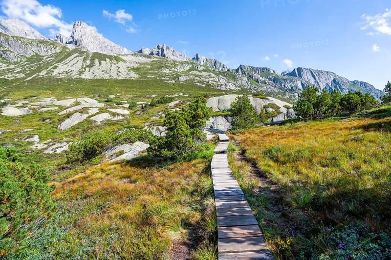Wooden plank trail through mountain moor, in front of picturesque mountain landscape, Göscheneralp, Canton of Uri, Switzerland