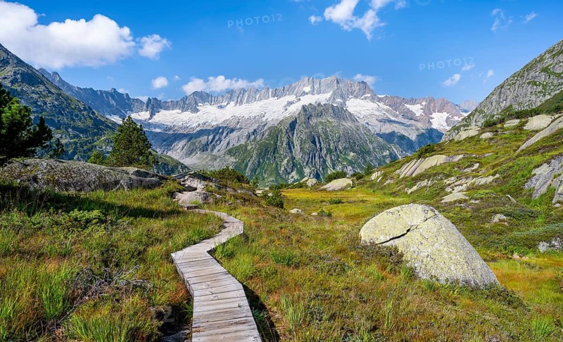 Wooden plank trail through mountain moor, in front of picturesque mountain scenery, Dammastock and Damma glaciers, Göscheneralp, Canton of Uri, Switzerland