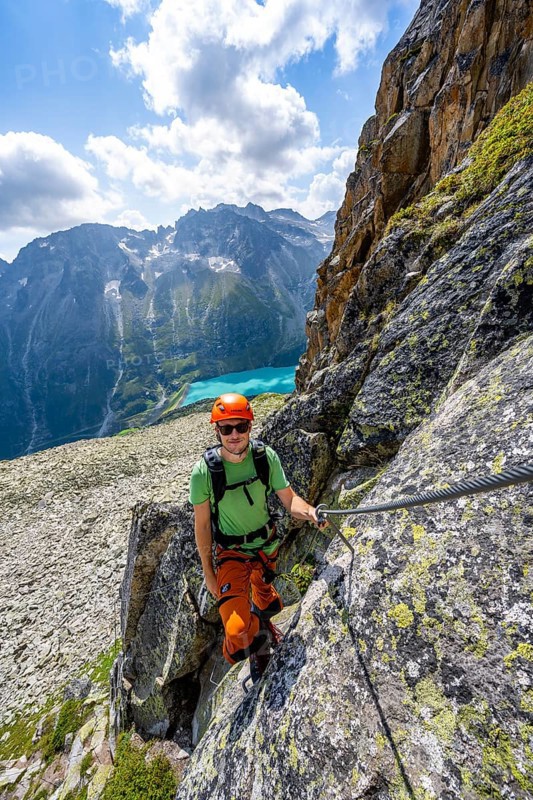 Mountaineer climbs on steep rock face in the secured via ferrata Crocodile Mountain Lake at Bergseeschijen-Vorbau, Göscheneralp, Canton of Uri, Switzerland