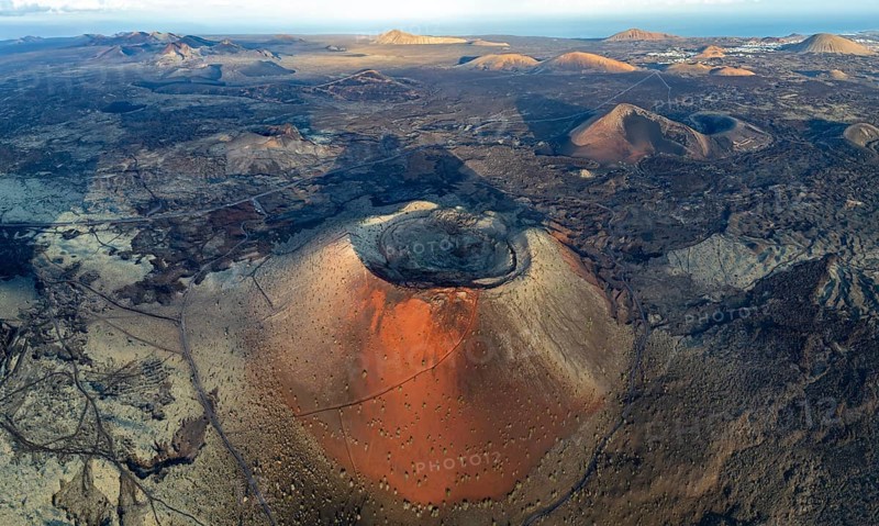 Caldera Colorada volcano, picturesque volcanic landscape with volcanic craters and lava fields in morning light, Parque Natural de Los Volcanes, aerial view, Lanzarote, Canary Islands, Spain