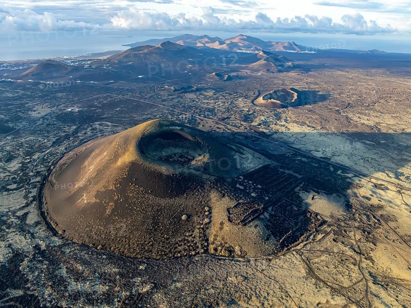 Montaña Negra volcano, picturesque volcanic landscape with volcanic craters and lava fields in morning light, Parque Natural de Los Volcanes, aerial view, Lanzarote, Canary Islands, Spain
