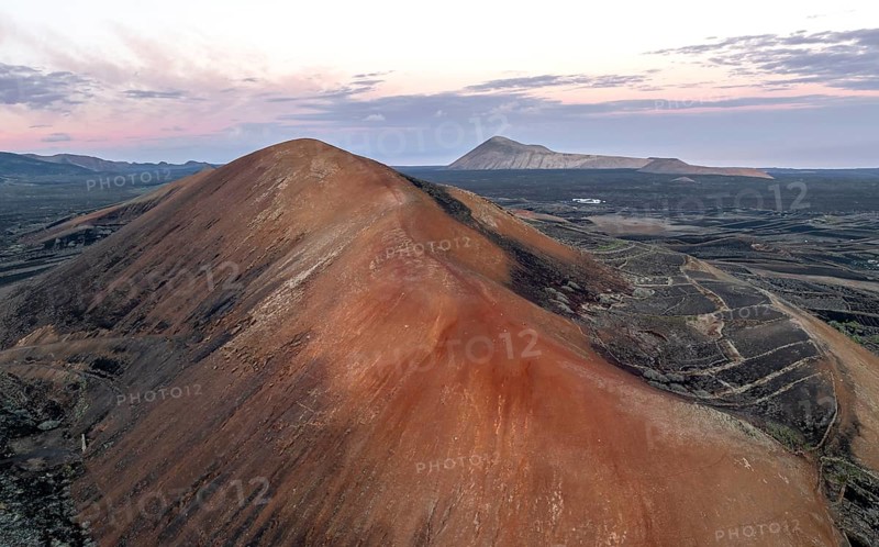 Red volcano Montaña Corujo, picturesque volcanic landscape with volcanic craters at sunrise, Parque Natural de Los Volcanes, aerial view, Lanzarote, Canary Islands, Spain