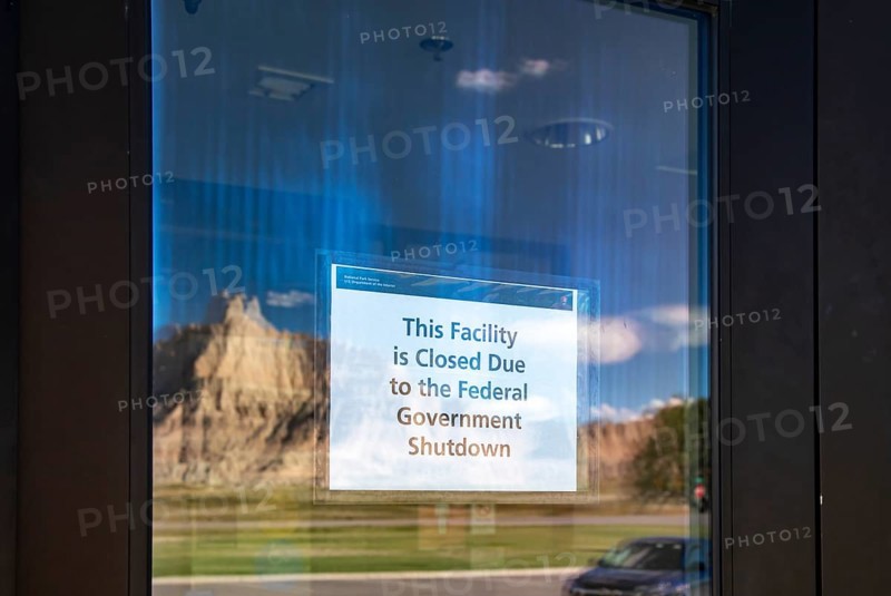 Badlands National Park, South Dakota - Badlands rock formations are mirrored in the door of the Badlands National Park Visitor Center. A sign announces that the facility is closed due to the 2025 government shutdown