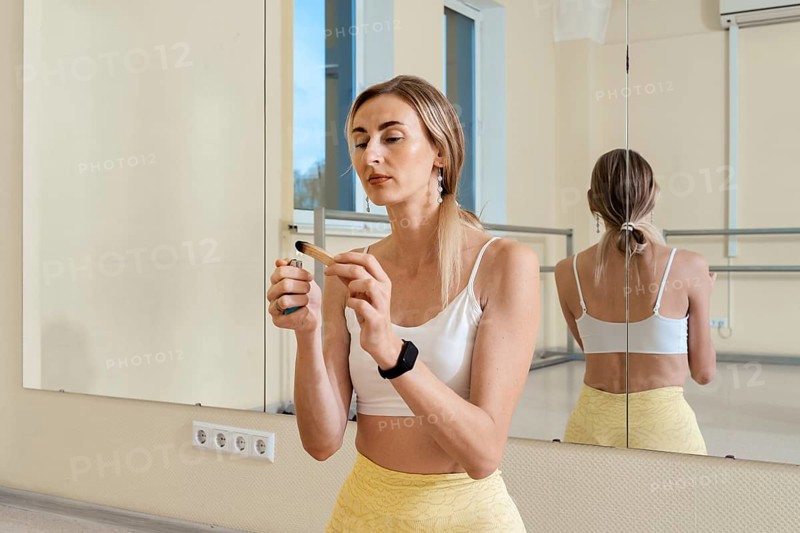 In a bright studio, a woman wearing a white top and yellow pants ignites palo santo the incense stick