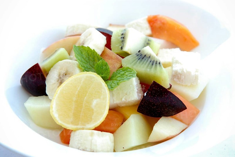 Fresh fruit salad with lemon, banana, papaya, kiwi, plums, melon and mint leaves in a bowl, Palace Hotel Devigarh, Delwara village near Udaipur, Rajasthan, India
