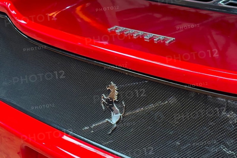 Close-up cutout detail part of red rear rear end of sports car Supercar Ferrari with logo trademark of luxury car manufacturer Jumping horse Cavallino Rampante, international