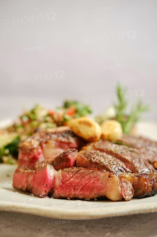 Juicy grilled steak medium rare on a white plate, with tender pink meat visible