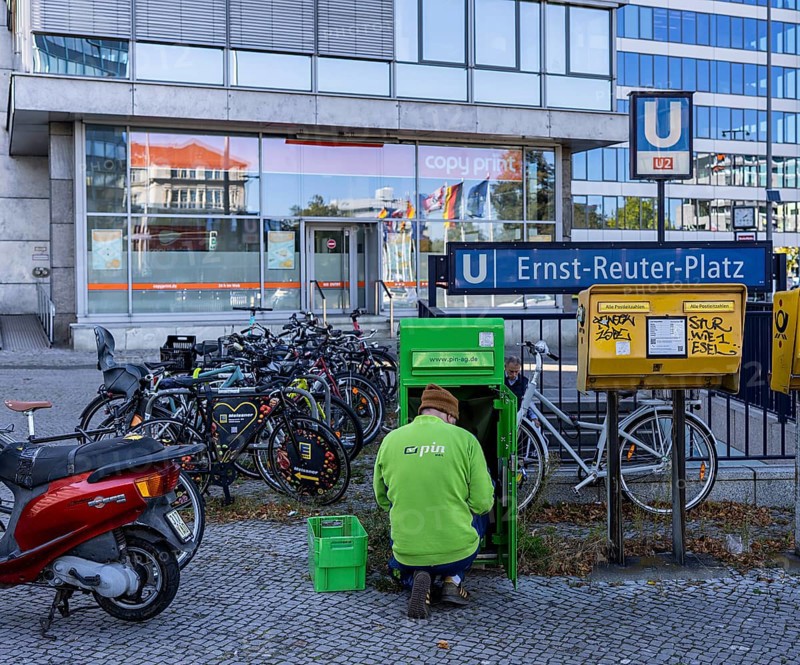 Pin Ag employees at a green mailbox in front of the subway entrance at Ernst Reuter Platz, Berlin, Germany