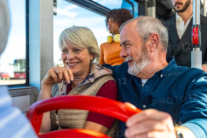 Senior husband and wife smiling and chatting on a daytime city bus, enjoying public transport together on a relaxed outing, comfortable, content, and engaged with each other
