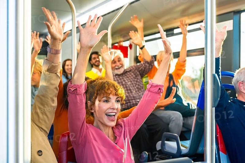 Diverse group of smiling passengers celebrating and cheering with arms raised inside a public transport bus, sharing a moment of joy and excitement during their commute