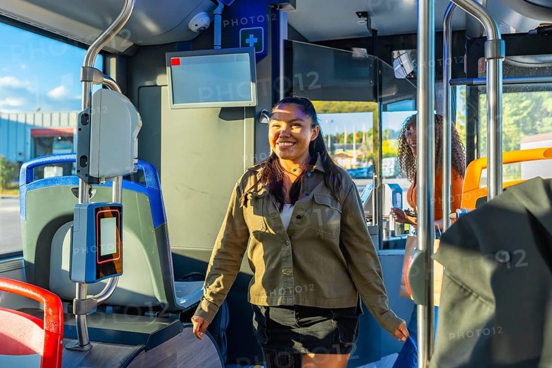 Woman smiling and walking inside a modern city bus, preparing for her daily commute, representing urban lifestyle, public transport convenience, and happy travel experience