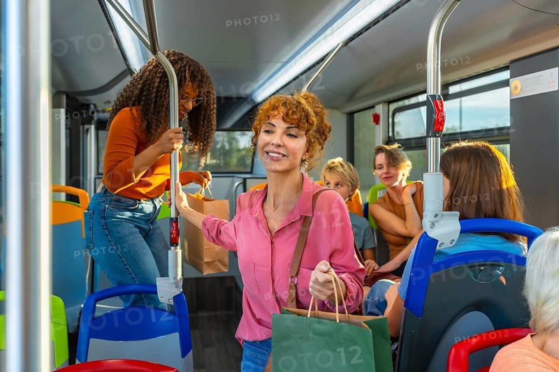 Diverse group of women and other people traveling on a public transport bus, some carrying shopping bags, representing daily commute, shopping errands, and urban lifestyle