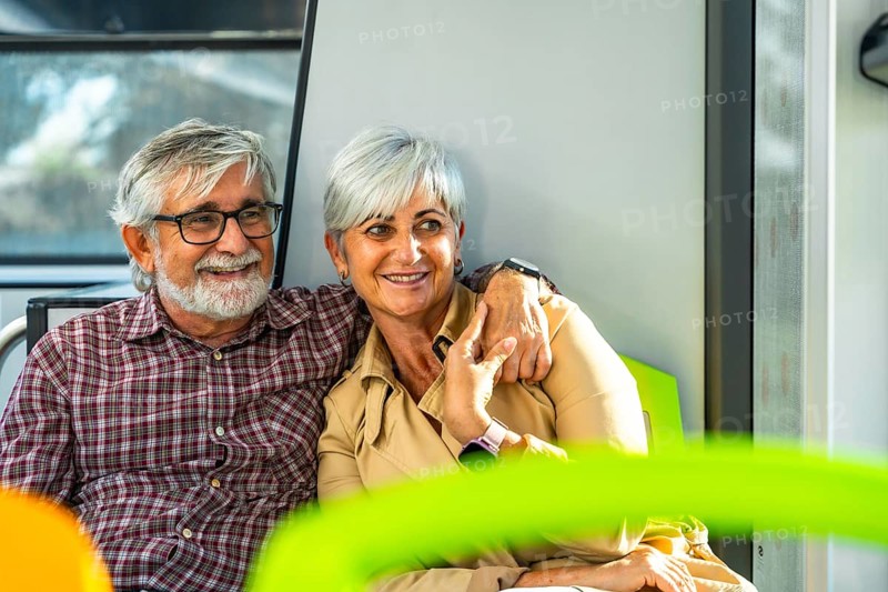Senior couple embraces on a city bus, smiling and enjoying retirement travel together, warm companionship and cheerful moments as they sit side by side during their journey