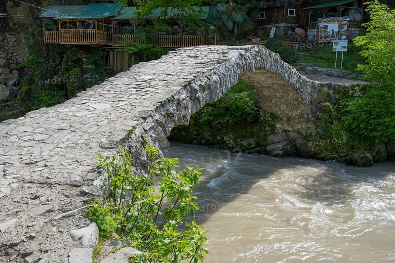 Historic stone bridge crosses bubbling river in forest, Makhuntseti stone arch bridge, Adjaristskali river, Adjara, Adjaria, Lesser Caucasus, Georgia