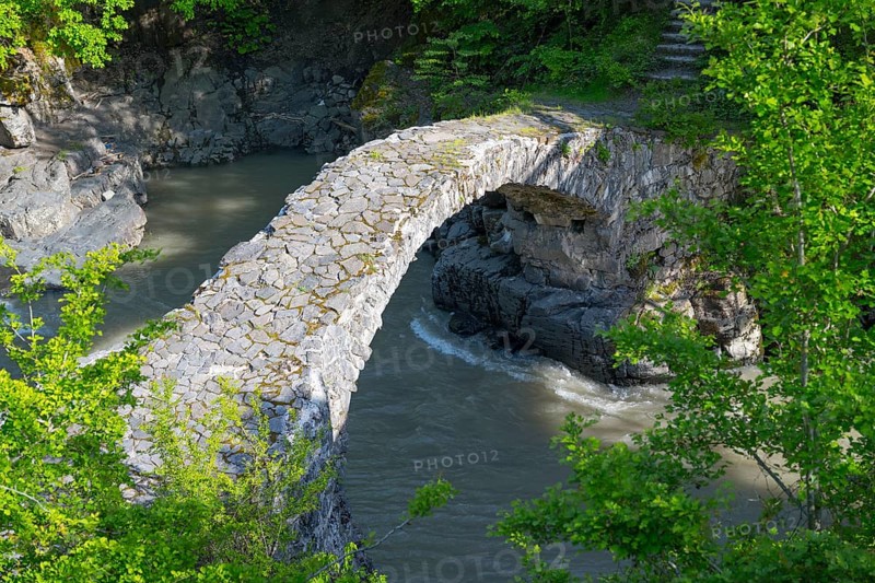 An old stone bridge spans a river amid green trees and rocks, Purtio stone arch bridge, Adjaristskali river, Adjara, Adjaria, Lesser Caucasus, Georgia