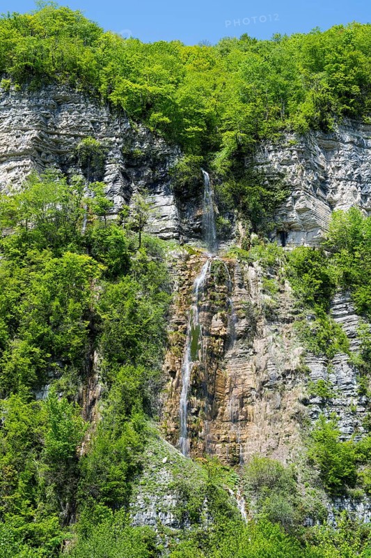 Small waterfall flows over a steep rock face surrounded by green forest, Okatse waterfall, Kinchkha waterfall, waterfall in three stages, Satsikvilo gorge, Imereti region, Imereti, Georgia