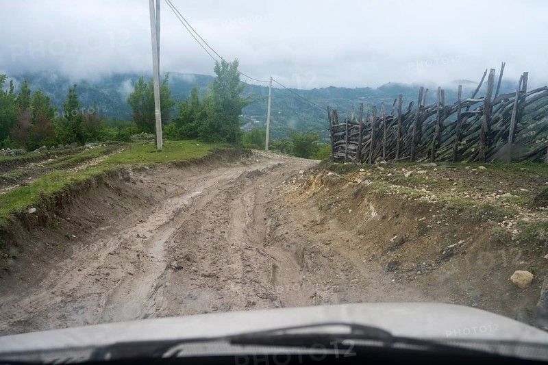 Muddy dirt road in a rural area leads through nature, four-wheel drive Lada, Imereti region, Imereti, Georgia