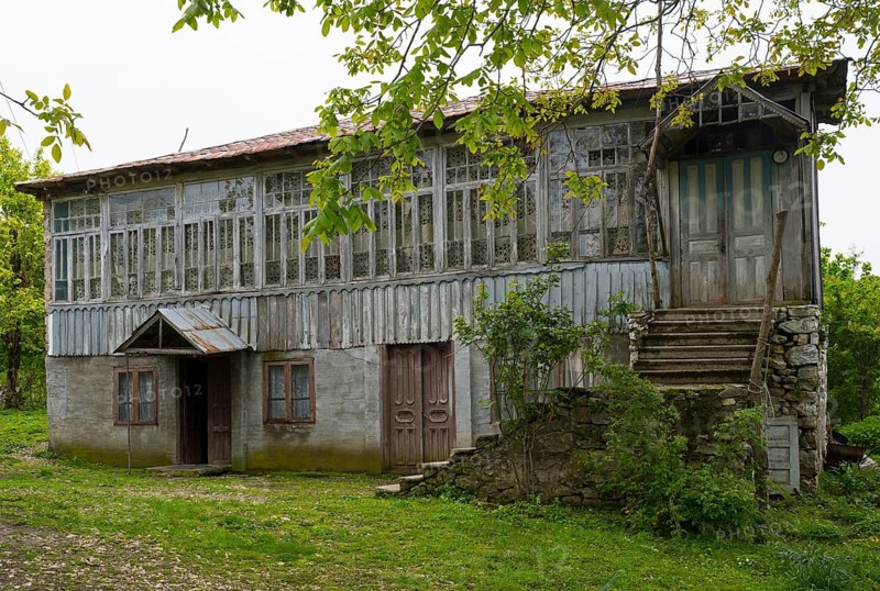 Old wooden house with lots of windows surrounded by trees in the countryside, Imereti region, Imereti, Georgia