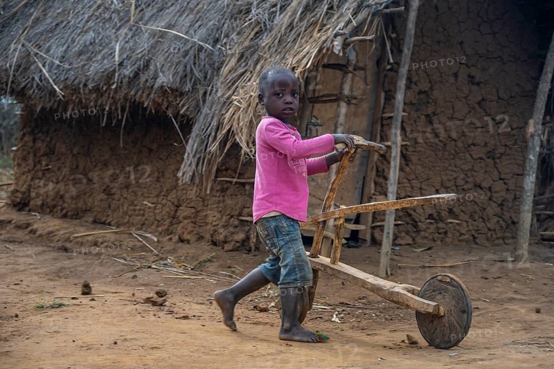 Child playing with a self-made wooden balance bike, in a Sadaani village, Tanga, Tanzania