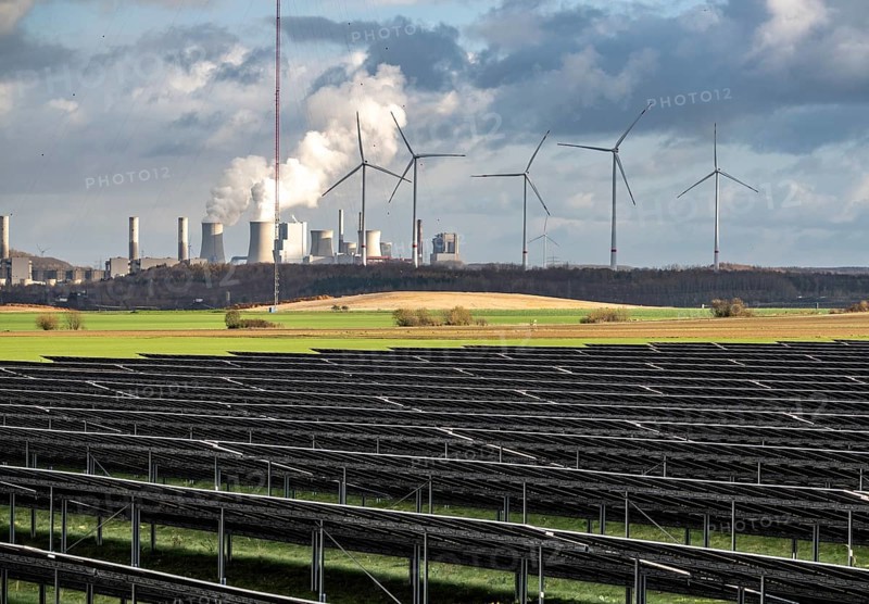 86.5 MW peak open space photovoltaic systems, from RWE, with over 141, 000 solar modules, on a side strip, along the A44 motorway near Jüchen, at the timber triangle, recultivated open-cast mining site, in the background RWE Neurath lignite power plant, wind farm, North Rhine-Westphalia, Germany