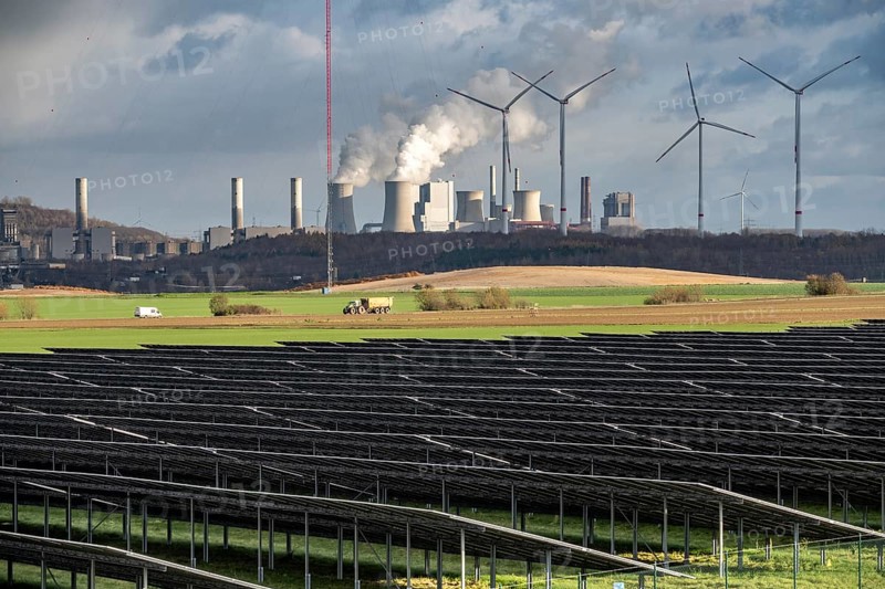 86.5 MW peak open space photovoltaic systems, from RWE, with over 141, 000 solar modules, on a side strip, along the A44 motorway near Jüchen, at the timber triangle, recultivated open-cast mining site, in the background RWE Neurath lignite power plant, wind farm, North Rhine-Westphalia, Germany