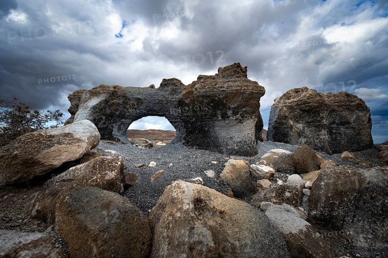Eroded rock formations with rock tunnels, volcanic landscape with dramatic cloudy skies, Ciudad Estratificada or Los Roferos, Antigua Rofera de Teseguite, Lanzarote, Canary Islands, Spain