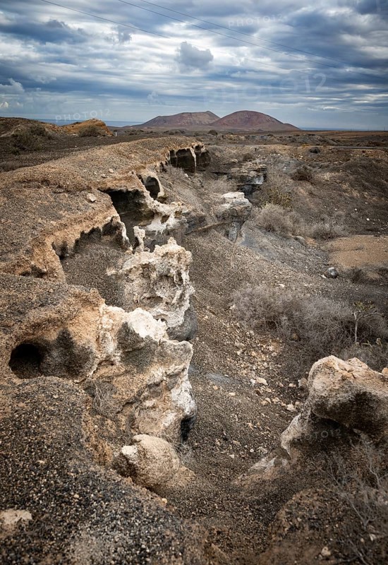 Eroded rock formations in volcanic landscape with dramatic cloudy skies, Ciudad Estratificada or Los Roferos, Antigua Rofera de Teseguite, Lanzarote, Canary Islands, Spain