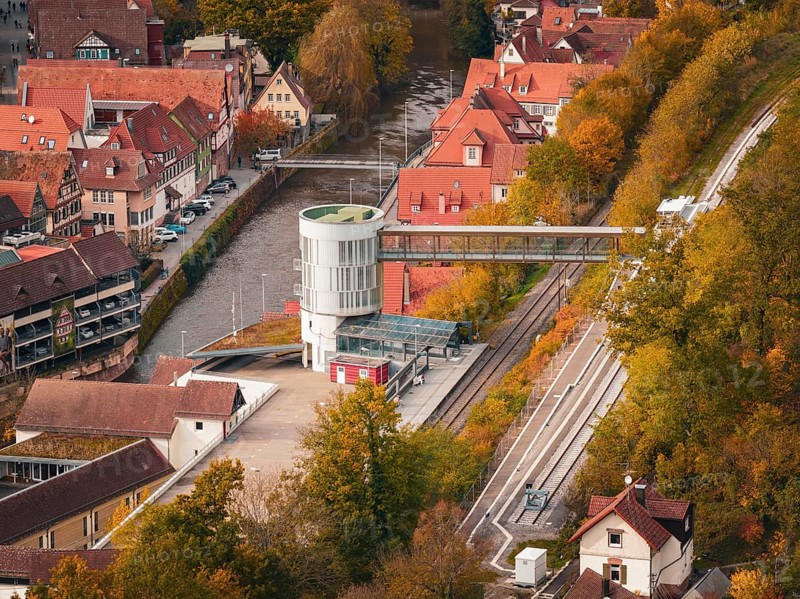 Station building with bridge across river, surrounded by autumn leaves and traditional houses, Calw, Black Forest, Germany