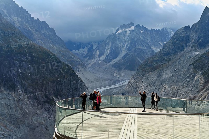 A group of people take pictures of themselves on the viewing platform in front of the Mer de Glace glacier, Mont-Blanc, Chamonix-Mont-Blanc, Haute-Savoie, France