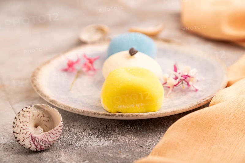 Japanese Mochi Cakes on brown concrete background and orange textile, side view, close up, selective focus